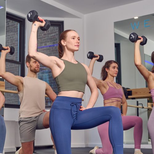 Four people lifting dumbbells during a Physique 57 class