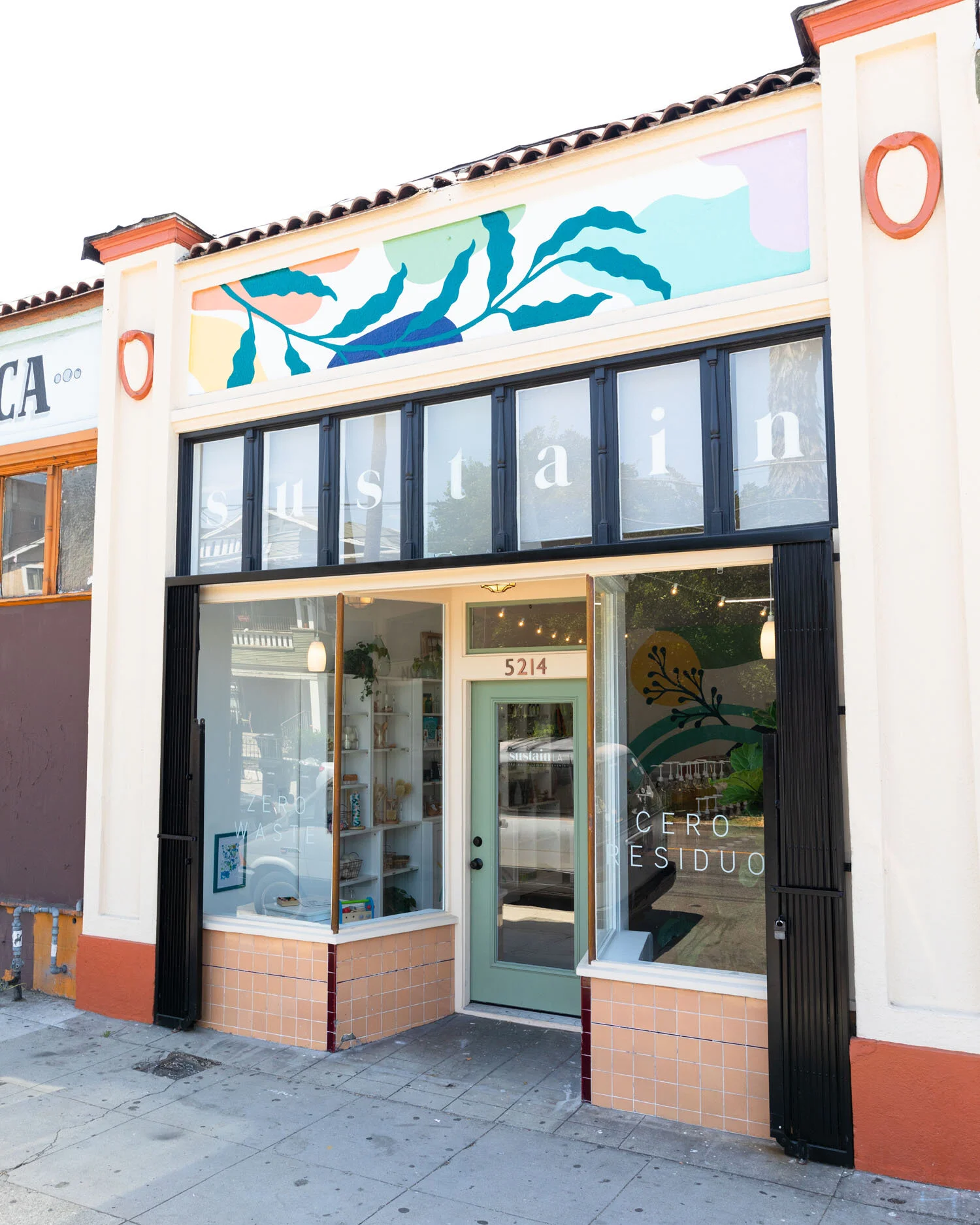 Sustain LA storefront exterior with colorful botanical mural and green door