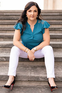 Wendy Paige Sterling in a teal top and white pants on stone steps