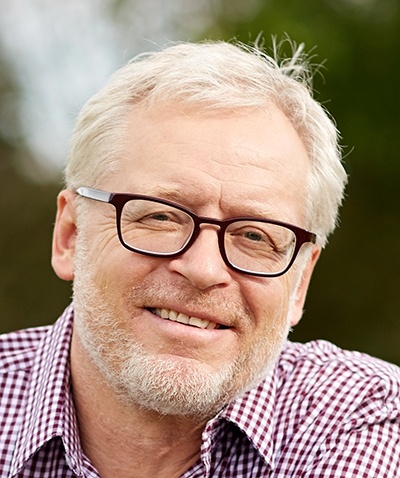 Paul S., older man with white hair, beard and glasses, smiling
