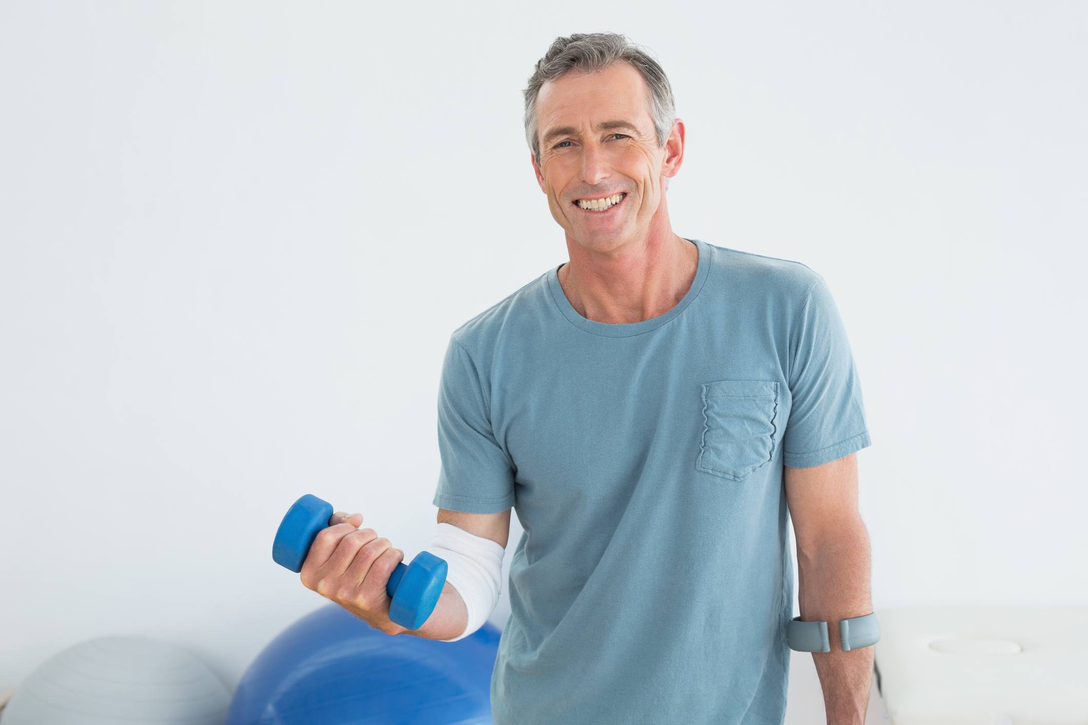 Smiling man holding a blue dumbbell during a therapy session