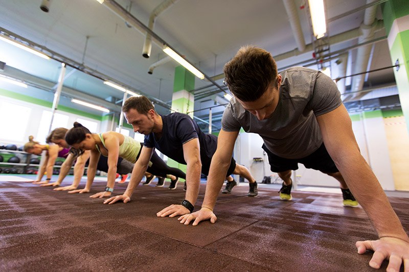 Group of people doing push-ups in a row on a gym floor