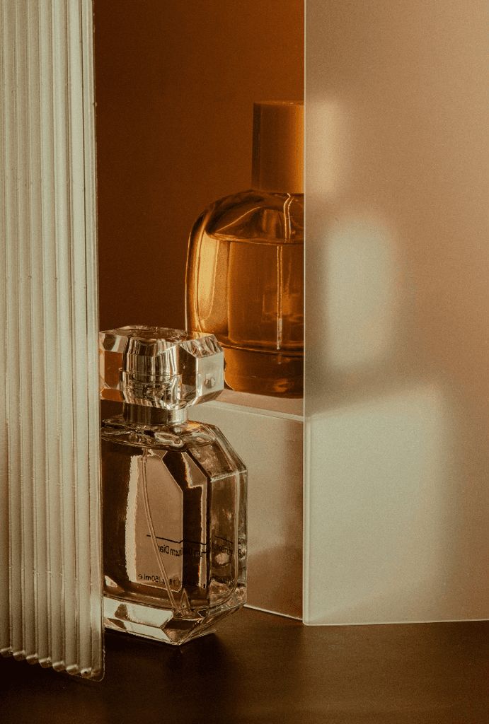 Glass perfume bottle on a dark shelf in amber light