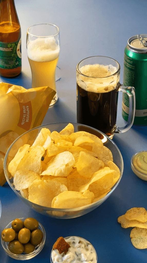 Chips, beer and snacks on a blue surface