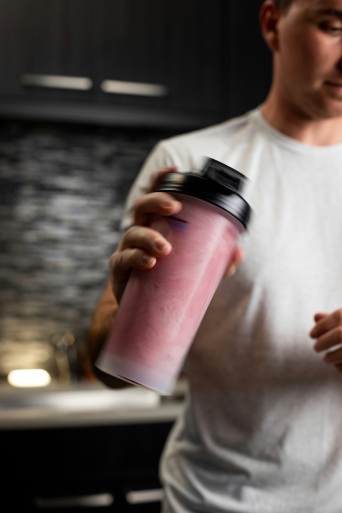 Man holding a pink protein shaker bottle