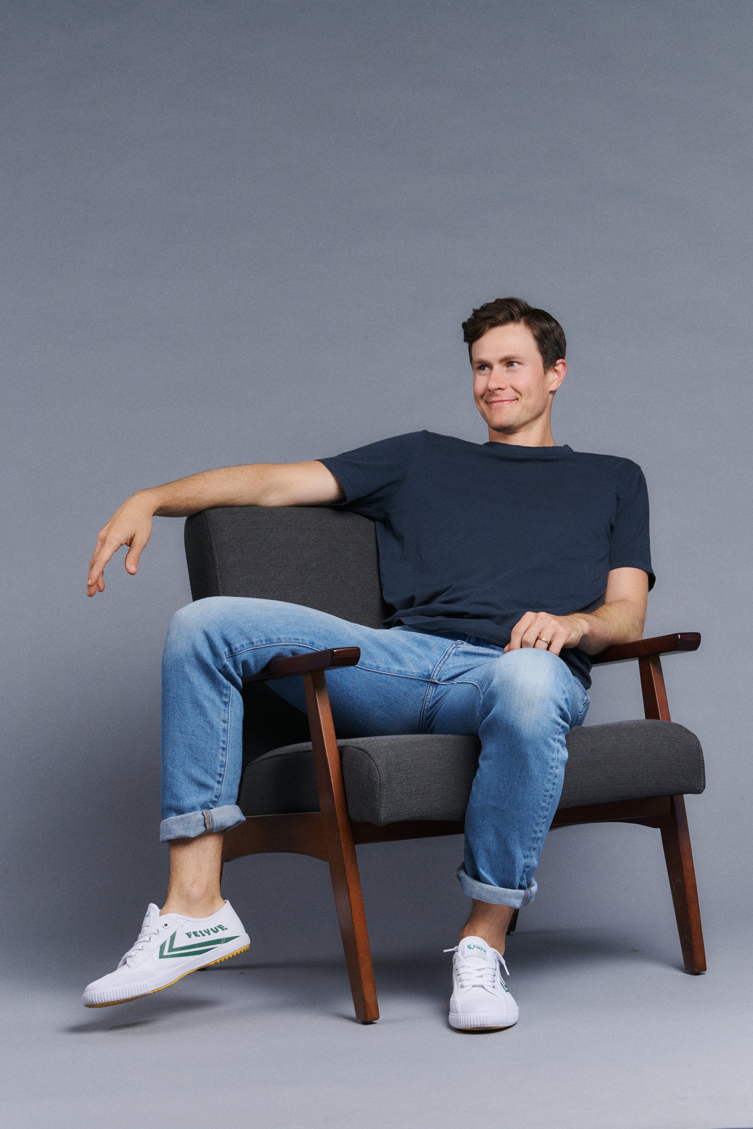 Kevin Munhall seated in an armchair against a grey studio backdrop