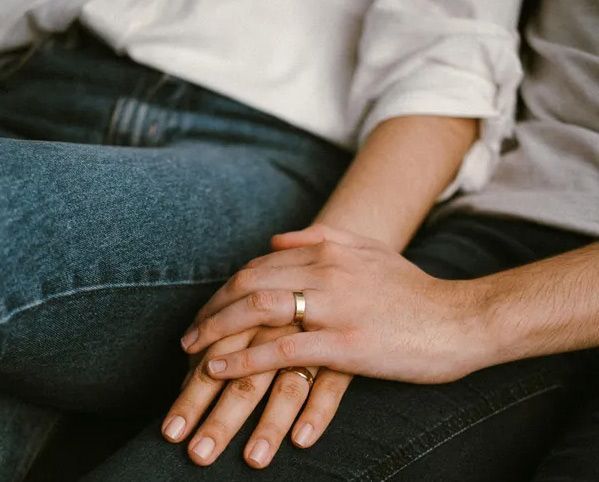 Two hands resting together, wearing wedding rings