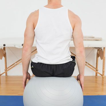 Man seated on a therapy ball during a physical therapy session
